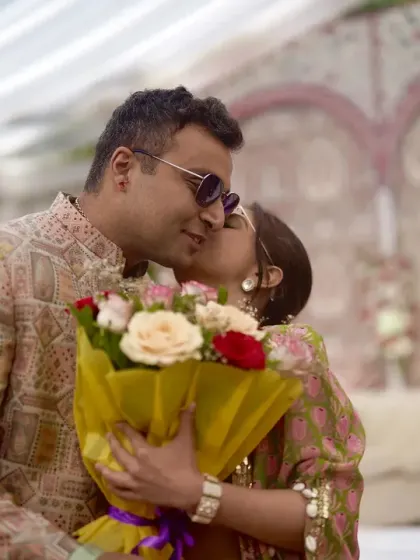 The groom surprises the bride with a bouquet of roses during their pre-wedding festivities.