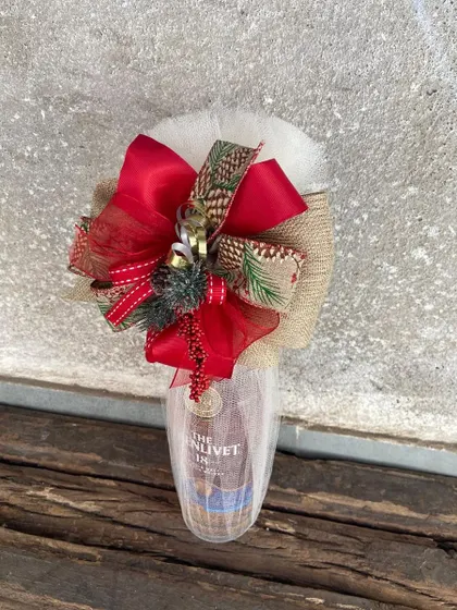 A festive bottle of The Glenlivet, wrapped for the holidays with a red bow and pinecone-printed ribbon. This shows how we tailor our bottle wrapping for any seasonal celebration.