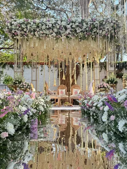 A modern fairy tale comes to life. This mandap combines a reflective mirror aisle with a cascade of lilac and white florals, creating a breathtaking space for you to say your vows.
