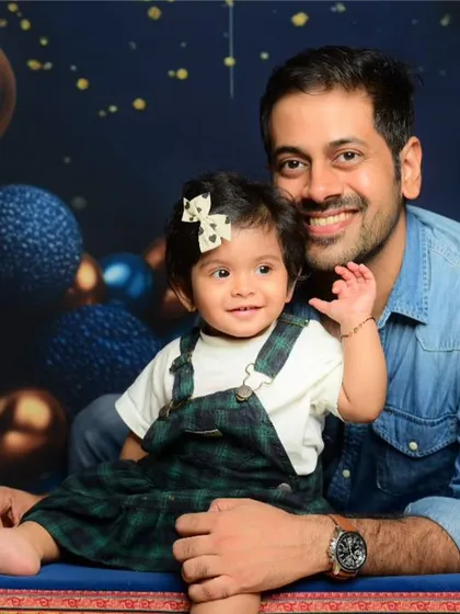 A heartwarming father and daughter portrait against a festive studio backdrop.