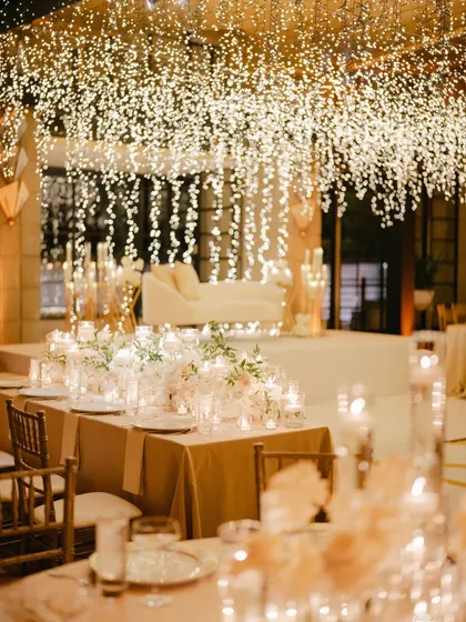 A beautiful shot of the reception decor. The tables are set under a ceiling of cascading fairy lights, creating a magical and romantic ambiance for the evening.