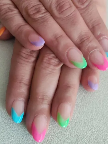 A playful and modern take on the French manicure, with vibrant, multicolored tips in shades of pink, green, blue, and purple.