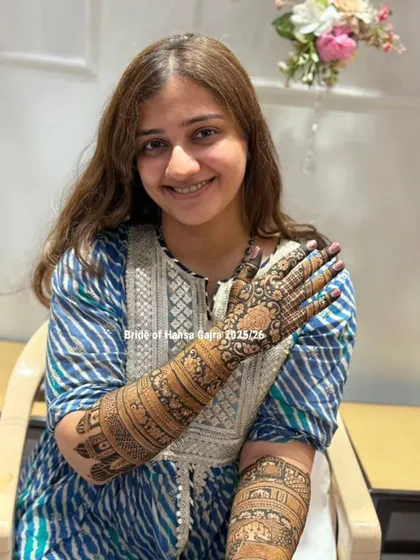 A graceful pose from a bride, showcasing her full-arm mehendi. Her calm and happy expression reflects the beauty and tradition of the art she wears.
