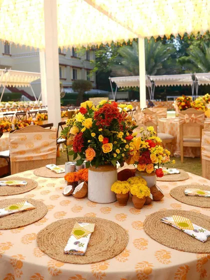 The guest tables at the Haldi featured jute placemats, custom-printed napkins, and beautiful centerpieces of red and yellow flowers.