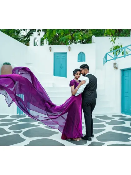 A romantic embrace in a beautiful white and blue setting. The bride's flowing purple gown adds a touch of regal elegance to the scene.