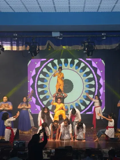 A wide shot of the Devi Maa prayer act, showing the full scale of the performance with multiple students and intricate formations on stage.