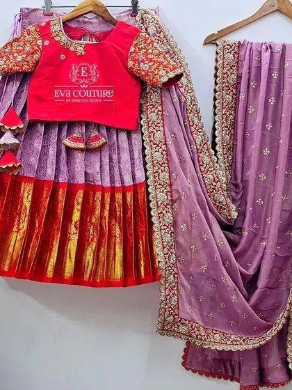 A complete Kanchi pattu lehenga set with a heavy work dupatta. The red blouse and lavender skirt are complemented by a beautiful lilac dupatta with an intricate scalloped maggam work border.
