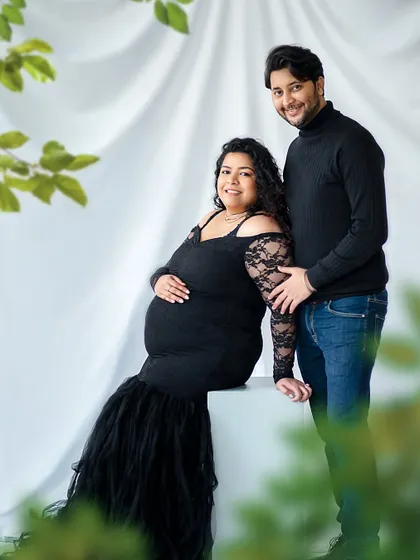 A classic and elegant maternity portrait. The black lace dress and the soft, leafy foreground create a look that is both timeless and romantic.