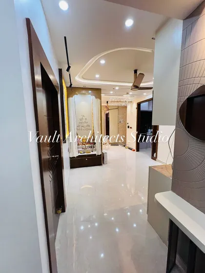 A view down the hallway of a newly completed apartment. This image captures the cohesive design language, from the polished floors and elegant pooja mandir to the textured wall panels in the living area.