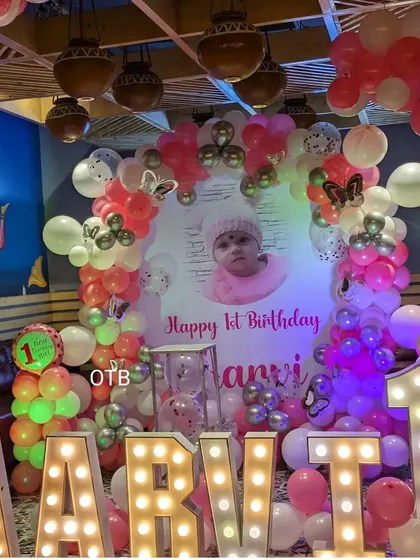 A pink and white butterfly theme for Aarvi's first birthday, with large light-up letters and a custom photo backdrop.