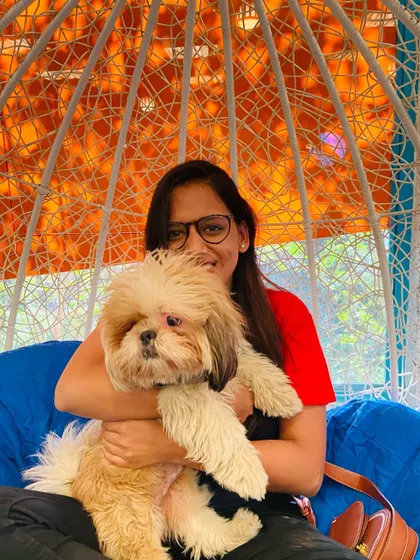 A furry companion makes everything better. A guest enjoying a cuddle with her fluffy Shih Tzu in our popular wicker swing chair.