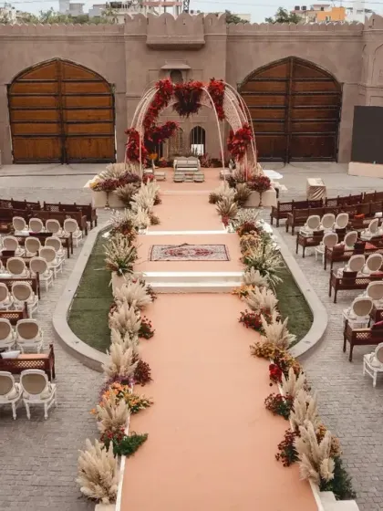 An aerial view of the grand wedding setup at Fairmont Jaipur. The long aisle, flanked by pampas grass and florals, leads to a stunning mandap, designed for a regal and memorable ceremony.