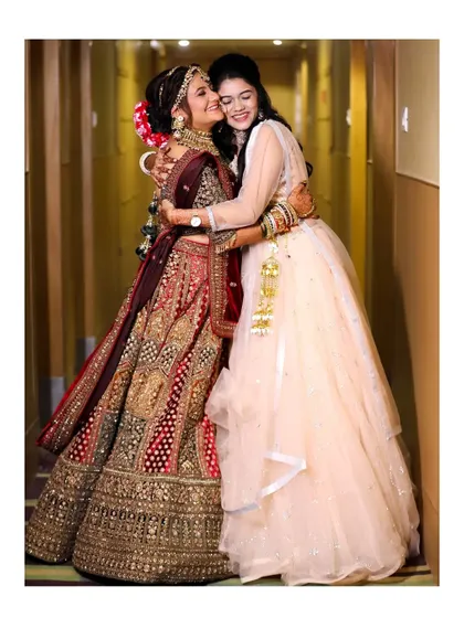 A full-length shot of the bride and bridesmaid sharing a warm hug. This image beautifully captures the emotion and support between friends.