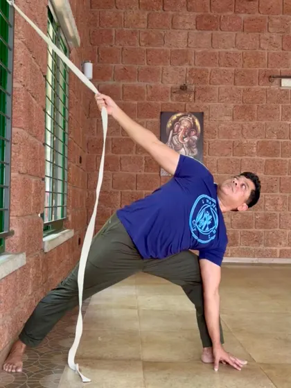 Using a strap as a prop in Parsvakonasana (Side Angle Pose) helps to extend the spine and open the chest, allowing for a deeper experience of the asana with proper support.