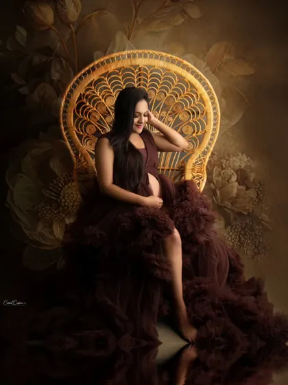 A beautiful, reflective pose on the peacock chair. The water-like reflection on the floor adds an artistic touch to this maternity portrait.