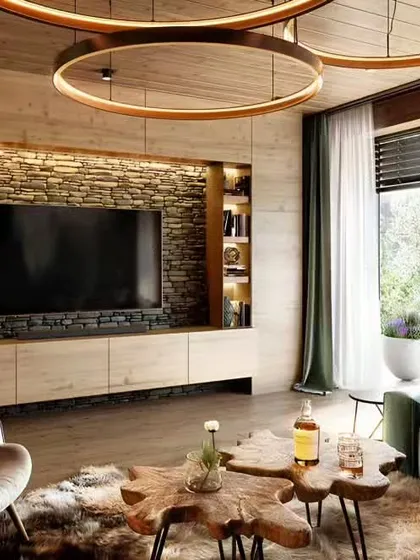 A rustic yet modern living room featuring a stacked stone accent wall for the TV unit. The design is complemented by a natural wood coffee table, comfortable seating, and large windows that connect the indoor space with the outdoors.