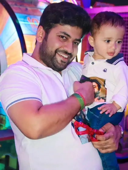 A father smiles for the camera while holding his young son at a party. We capture the happy, relaxed moments between parents and their children.