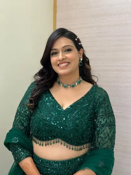 A stunning look in an emerald green lehenga, with soft glam makeup and beautiful curls.