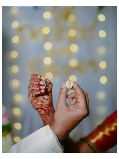 A beautiful detail shot from an engagement ceremony. The couple's hands come together to show off their new rings, with a soft, romantic bokeh background.
