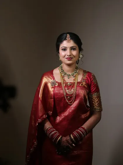 A stunning portrait of a Coorgi bride in a rich red silk saree. Her makeup is glamorous, with a focus on her eyes and a beautiful lip color.