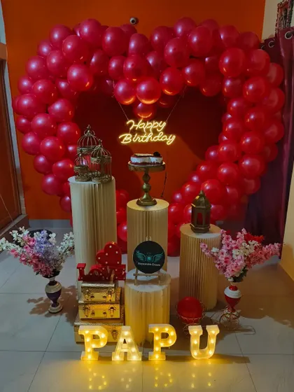 A beautiful red heart balloon arch with a 'Happy Birthday' neon sign.