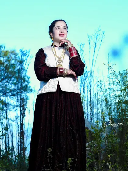 A full-length shot of a bride in her traditional Himachali reception outfit. The outdoor setting with the blue sky creates a beautiful contrast with her attire.