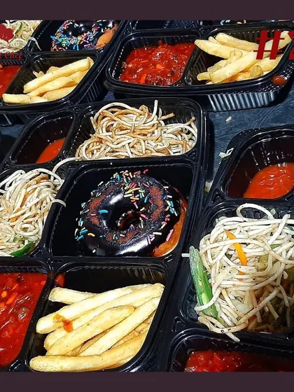 A look inside our Chinese-themed snack boxes, featuring noodles, french fries, a savory sauce, and a donut with sprinkles.