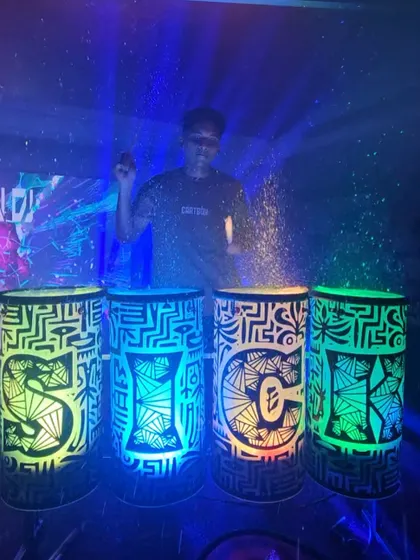 The "SICK" liquid drums under blue lighting, with water splashing from the tops, creating a misty, atmospheric effect.
