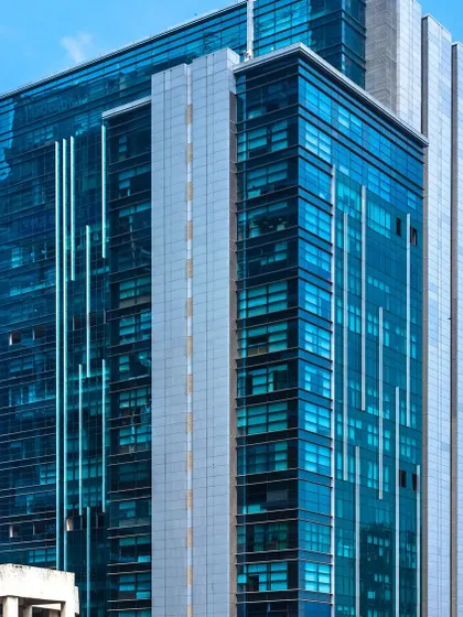 A facade detail of Naman Midtown, showing the sleek glass curtain wall and vertical design elements. This 21-floor tower is a prime example of modern corporate architecture designed to make a strong impression in a dense urban business district.