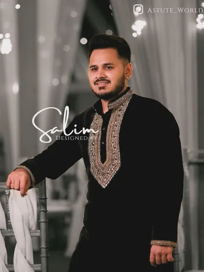 A client in a black velvet kurta with a heavily embroidered gold neckline and cuffs. This is a classic, regal look suitable for a wedding reception or formal dinner.