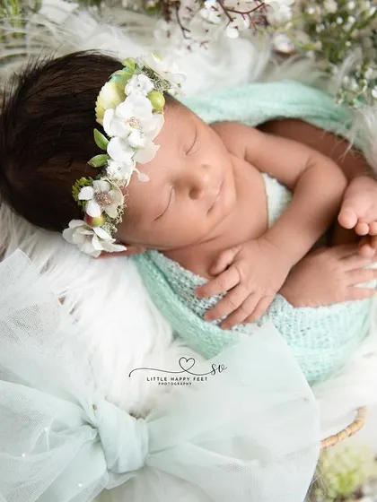 Wrapped in sea green and surrounded by white flowers. The large bow in the foreground adds a beautiful framing element and a touch of elegance.