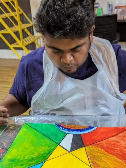 A participant working on a geometric abstract painting, carefully filling in the shapes with bold colors.