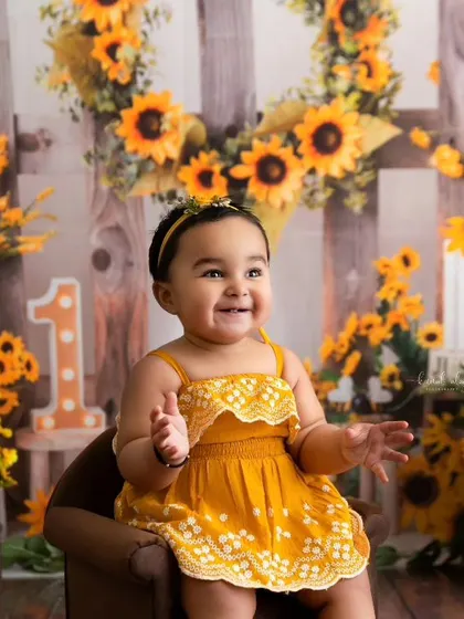 A joyful, clapping moment from the sunflower-themed first birthday shoot.