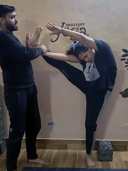 A student deepens her stretch in a variation of Standing Splits. This posture not only improves physical flexibility but also cultivates mental determination and patience.