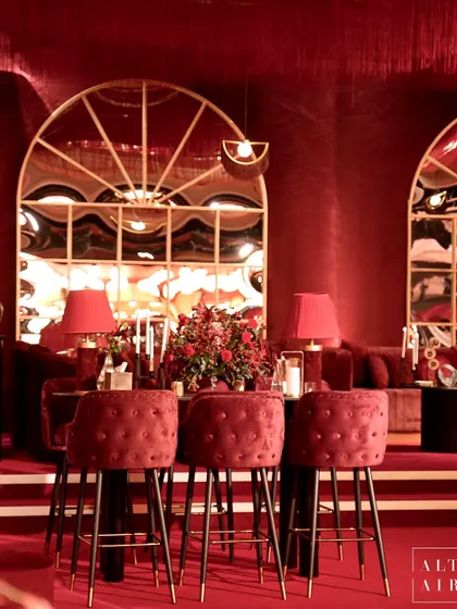 A high-top table at the 'Le Rouge' sangeet in Doha. The tufted velvet bar stools and arched mirrors added to the sophisticated, boudoir-inspired aesthetic.