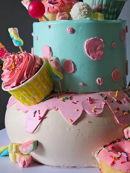 A detailed shot of the 100% whipped cream candyland cake, showcasing the piped cupcakes, donuts, and colorful candy decorations.