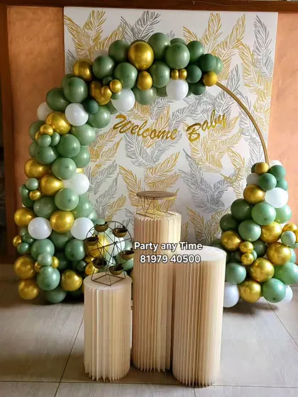 A nature-inspired balloon arch in green, gold, and white with a "Welcome Baby" sign.
