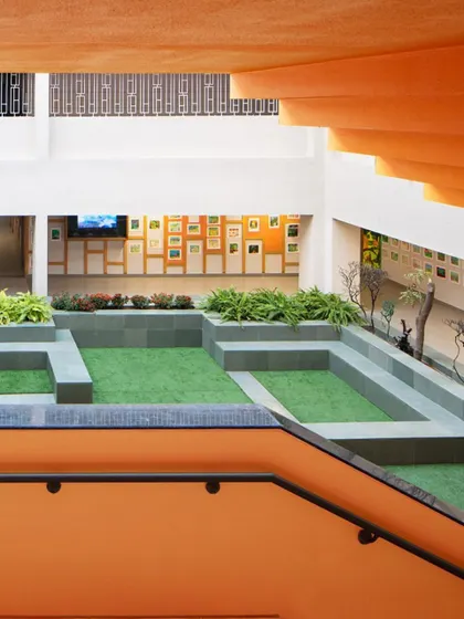 A view from the staircase reveals how the new design elements connect different levels of the school. The central courtyard, now filled with planters and seating, has become a green, vibrant hub for students during breaks.