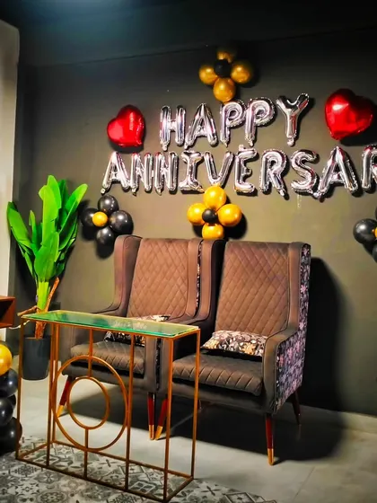 A simple yet stylish first-anniversary decoration. The setup includes "Happy Anniversary" foil balloons, a large number "1" balloon, and a black and gold color scheme.