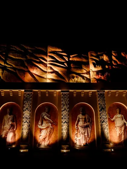 A wall featuring niches with Roman statues, illuminated from below. This architectural detail adds to the feeling of being in an ancient, excavated city.