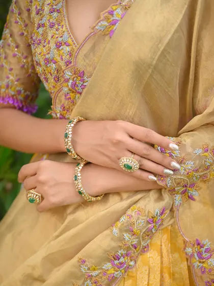 A detailed shot of the jewelry and the embroidered dupatta, complementing the gold and purple half saree.