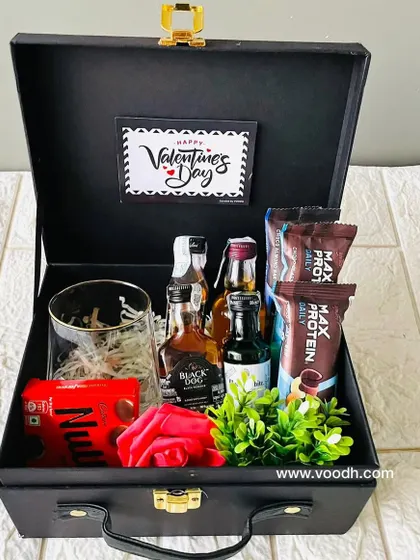 This Valentine's Day hamper for him features miniature alcohol bottles, protein bars, and a stylish glass, all neatly arranged in a black suitcase box.