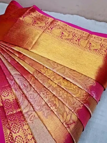 A close-up of the intricate patterns on a pink and gold silk saree. The pleats are perfectly fanned out to showcase the beautiful workmanship.