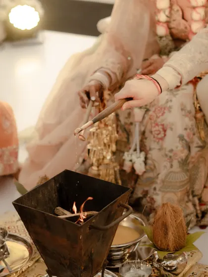 A close-up of the sacred fire (havan) at the heart of the wedding ceremony, with the couple's hands seen performing the ritual. A symbol of their holy union.