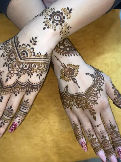 This showcases a modern Arabic mehandi style. The design uses negative space effectively, with flowing vines and bold floral elements on the hands and wrist for a chic and contemporary feel.