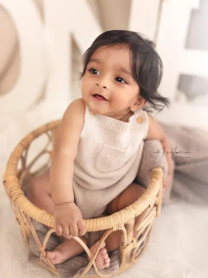 A classic sitter portrait of a smiling baby in a rustic wicker basket. These sessions, best between 8-10 months, are perfect for capturing your baby's emerging personality.