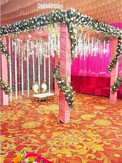 A beautiful mandap decorated with pink drapes and hanging white flowers. The traditional heart-shaped chairs for the bride and groom are a lovely detail.