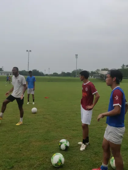 A coach provides instruction during a ball control drill, with players listening intently. This highlights the hands on coaching approach I use.