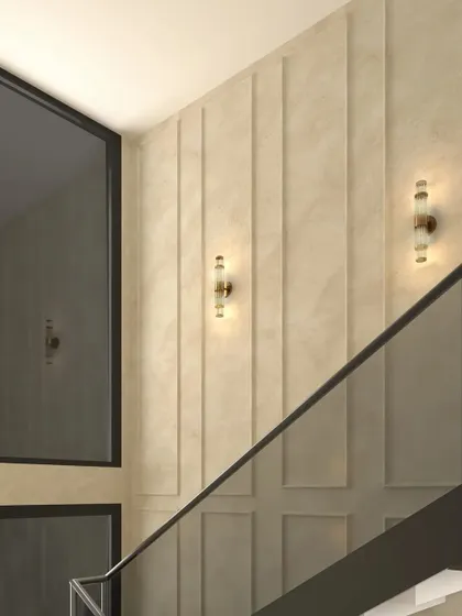 The wall along the staircase features elegant molding and modern sconce lights, adding a touch of classic sophistication.