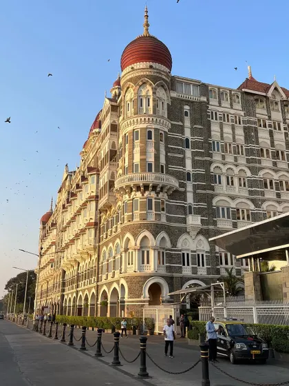A street-level view of the corner of the Taj Mahal Palace, capturing its grandeur and the daily life happening around it.